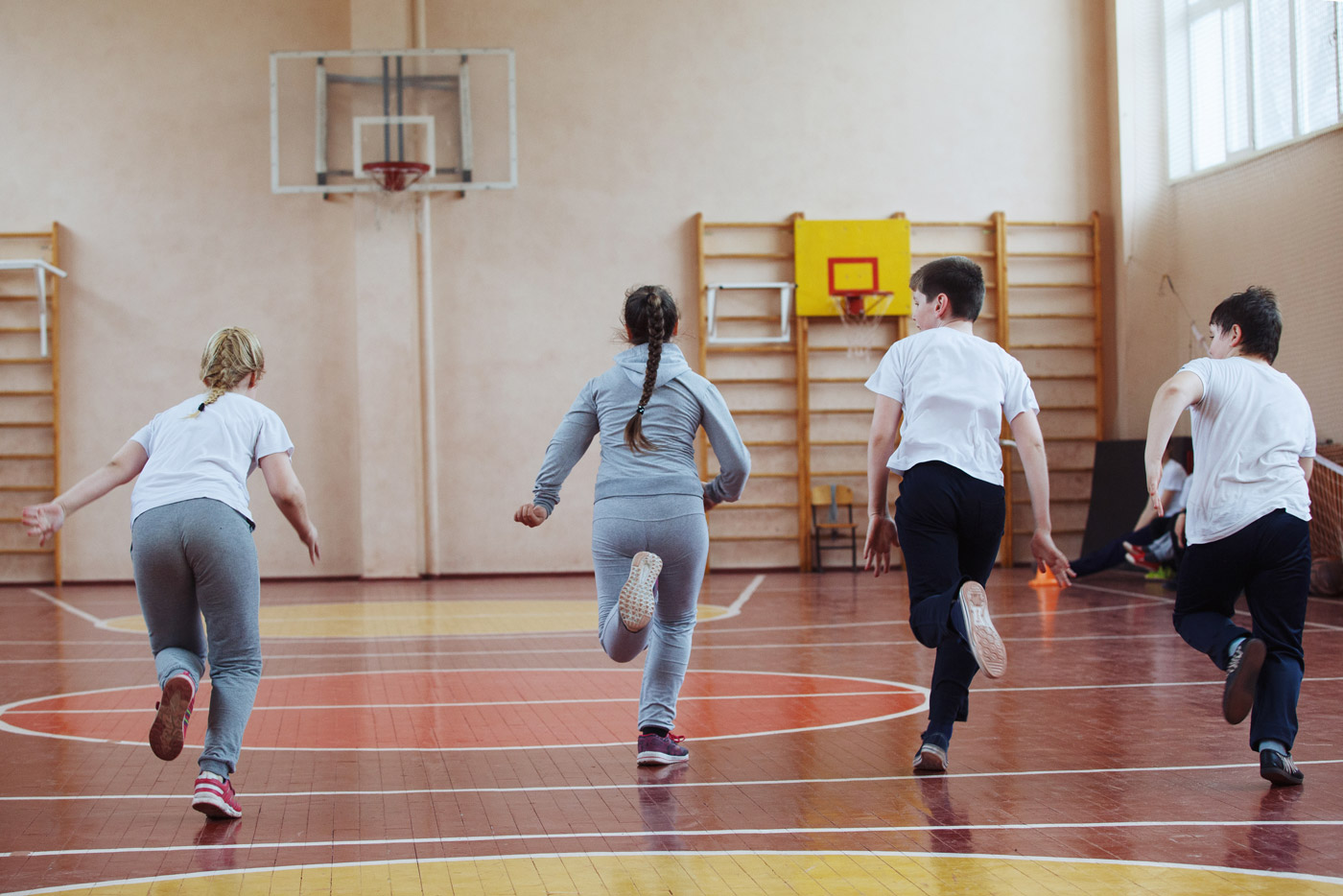 Kinder laufen in einer Turnhalle in Sportkleidung