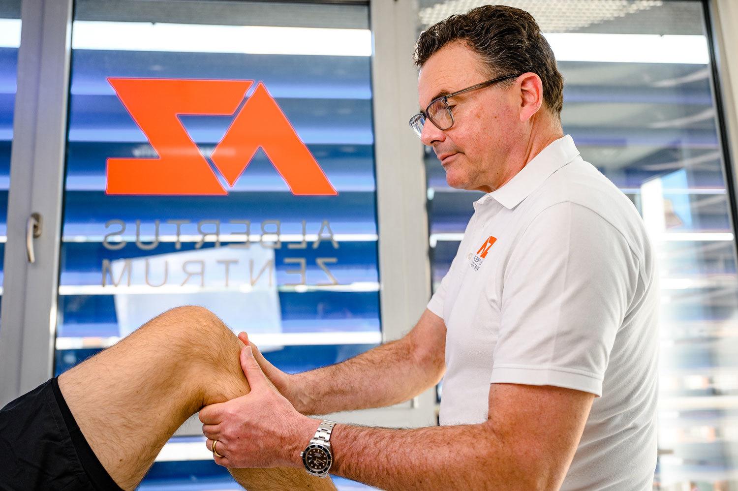 Orthopäde Dr. med. J. Heussen untersucht das Kniegelenk eines Patienten